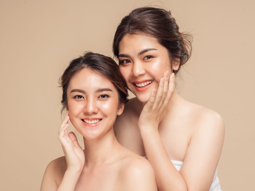 베이지색 배경 앞에 선 두 여성의 인물 사진